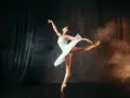 Tancerka w białej tutu w pozie na scenie. To jest balet – sztuka ruchu, emocji i piękna.