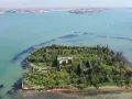 Un'isola verdeggiante con ruderi antichi, circondata da acque azzurre. Venezia è un'isola, e questa vista aerea ne mostra la bellezza selvaggia.