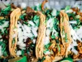 Fünf köstliche Tacos mit Rindfleisch und Hähnchen, garniert mit Zwiebeln und Koriander. Perfekt für einen Taco-Abend!