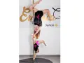 Dwie tancerki, dorosła i dziecko, wykonują akrobacje na słupie. To dowód, że pole dance dla dzieci to świetna zabawa i aktywność.