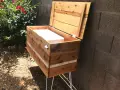 Wooden DIY deck box with lid open, showing white interior, on hairpin legs.