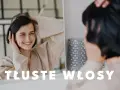 Uśmiechnięta kobieta dotyka swoich włosów, zastanawiając się, co zrobić, żeby włosy się nie przetłuszczały.
