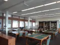 Salle de lecture avec tables, chaises et étagères de livres.