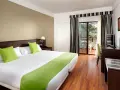 Pokój hotelowy z dwoma łóżkami, zielonymi poduszkami i widokiem na trh taoro garden.