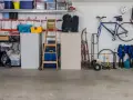 Garage med cykel, stegar, förvaringslådor och en liten fönsterlucka för ventilation.