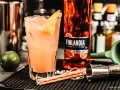Orzeźwiające drinki z Finlandia Redberry, idealne na letnie wieczory. W szklance różowy koktajl z lodem i skórką cytrusową.