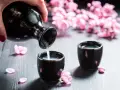Nalewanie sake do czarek, w tle kwitnące wiśnie. Zastanawiasz się, sake ile procent?