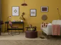 Un salotto con pareti giallo ocra e dettagli tortora. Un divano beige, un pouf tortora e un tappeto in juta creano un'atmosfera accogliente.