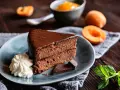 Ein Stück Sachertorte, das aussieht wie vom Original Sachertorte Rezept, mit Schlagobers, Schokolade und Marillenmarmelade.