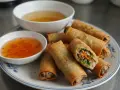 Chrupiące spring rolls z warzywnym farszem, podane z dwoma sosami. Idealne na przekąskę.
