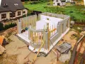 Budowa domu ze styropianu w toku. Ściany z bloczków betonowych i białego styropianu, zbrojenia i drewniane podpory.