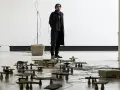 Tarek Atoui, artiste, se tient au milieu d'une installation sonore avec de nombreuses petites structures en pierre et en bois reliées par des câbles.