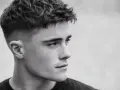Perfil de hombre joven con corte de pelo moderno, un degradado rasurado impecable que se funde con la piel.