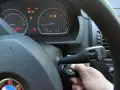 Ręka wkłada kluczyk do stacyjki, by dokonać kasowania błędów w samochodzie. Na desce rozdzielczej świecą się kontrolki.