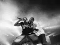 Deux rappeurs en pleine performance, l'un tenant un micro, l'autre le soutenant. Une scène intense qui illustre la puissance du hip hop en France.