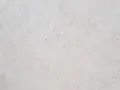 Surface texturée d'enduit chaux chanvre finition lisse, d'une teinte claire et naturelle, évoquant la douceur d'un mur sain.