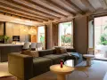 Sofá modular verde con acabado fratasado, mesas auxiliares, lámpara roja y acceso a patio con muebles de exterior.
