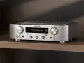 Srebrny wzmacniacz Marantz PM7000N, gotowy do testu, z wyświetlaczem pokazującym utwór muzyczny.