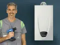 Installazione scaldabagno a gas normativa: un artigiano sorridente con trapano pronto per il lavoro, accanto a un nuovo scaldabagno.