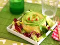 Causa limeña con aguacate en espiral y ensalada fresca, servida en plato blanco.