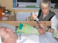 Kobieta podaje płyn przez strzykawkę choremu leżącemu w łóżku. Scena budzi pytania o co to eutanazji.