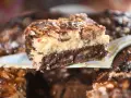Ein Stück saftiger "friss dich dumm kuchen vom blech" mit Schichten aus Schokolade, Käsekuchen und Nüssen wird serviert.