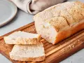 Ein Laib japanisches Reisbrot, aufgeschnitten auf einem Holzbrett. Dieses Rezept für japanisches Reisbrot ist perfekt für alle, die glutenfreies Brot lieben.