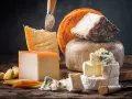 Kuski najlepsze sery: parmezan, pleśniowy, camembert i inne, ułożone na drewnianej desce.
