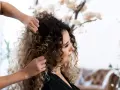 Stylista układa kręcone włosy klientki, przygotowując się do strzyżenia. Wskazówki, jak obciąć kręcone włosy, pomogą uzyskać idealny kształt.