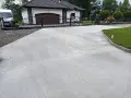 Nowy podjazd z betonu przed domem z garażem i bramą.