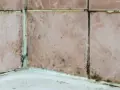 Moisissure noire et saleté sur les joints de carrelage rose dans un coin de salle de bain. Il est temps d'enlever l'odeur d'humidité de la salle de bain.