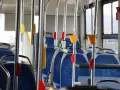 Wnętrze autobusu 139 z niebieskimi siedzeniami i metalowymi poręczami.