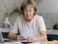 Frau mit Brille prüft Unterlagen und nutzt Taschenrechner. Sie informiert sich über welche rechte hat ein mieter nach 10 jahren.