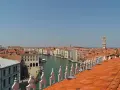 Vista dall'alto dei tetti rossi di Venezia, con il Canal Grande e le sue calli animate.