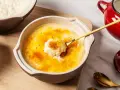 Delicioso arroz con leche asturiano con una capa crujiente de caramelo. Una cuchara dorada levanta una porción cremosa.