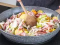 Zutaten für einen herzhaften Hamburger Pannfisch werden in einer Pfanne vermischt: Kartoffeln, Speck und Zwiebeln.