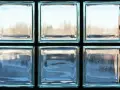 Un mur en brique de verre, reflétant la lumière extérieure, crée une ambiance douce et diffuse.