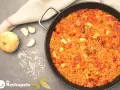 Arroz con calamares en paellera, con ingredientes como cebolla, ajo y pimientos. Un plato delicioso y lleno de sabor.