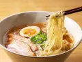 Parujące miseczka ramenu z makaronem, plastrami mięsa, jajkiem i szczypiorkiem. Idealne ramen przyprawy podkreślają smak.