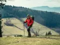 Mężczyzna w czerwonej kurtce i z plecakiem, gotowy do nordic walking. Jak zacząć? Wskazówki dla początkujących.