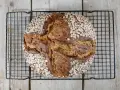 Ein rustikales Porridge Brot mit Haferflockenkruste, das auf einem schwarzen Gitter auf Holzdielen abkühlt.