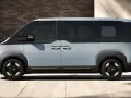 Jasnoszary elektryczny van Kia PV5 z czarnymi akcentami, widziany z boku.