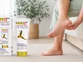 Kobieta masuje stopę, łagodząc ból związany z ostrogami piętowymi. Obok balsam Krok Med Foot Balsam.