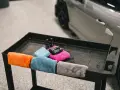 Kolorowe mikrofibry i buteleczki z preparatami do pielęgnacji auta. Tak prac mikrofibry, by auto lśniło.