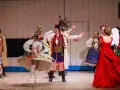 Rachela wesele w barwnych strojach ludowych, tańczący na scenie.