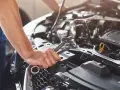 Mechanik sprawdza objawy awarii pompy paliwa Audi A4 B6 1.8T. W dłoni trzyma klucze.