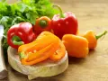Peperoni piccoli colorati, pronti per gustose ricette. Un coltello e prezzemolo completano la scena.