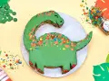 Grüne Dinosaurier Torte selber machen: Ein süßer Dino mit bunten Streuseln und Schokodrops. Perfekt für kleine Entdecker!