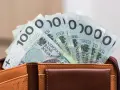 Portfel z banknotami 100 zł. Czy urlop wychowawczy jest płatny? To pytanie nurtuje wielu rodziców, a pieniądze w portfelu mogą pomóc w podjęciu decyzji.