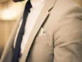 Elegancki mężczyzna w jasnej marynarce i granatowym krawacie. Zastanawiasz się, ile zarabia manager hotelu?